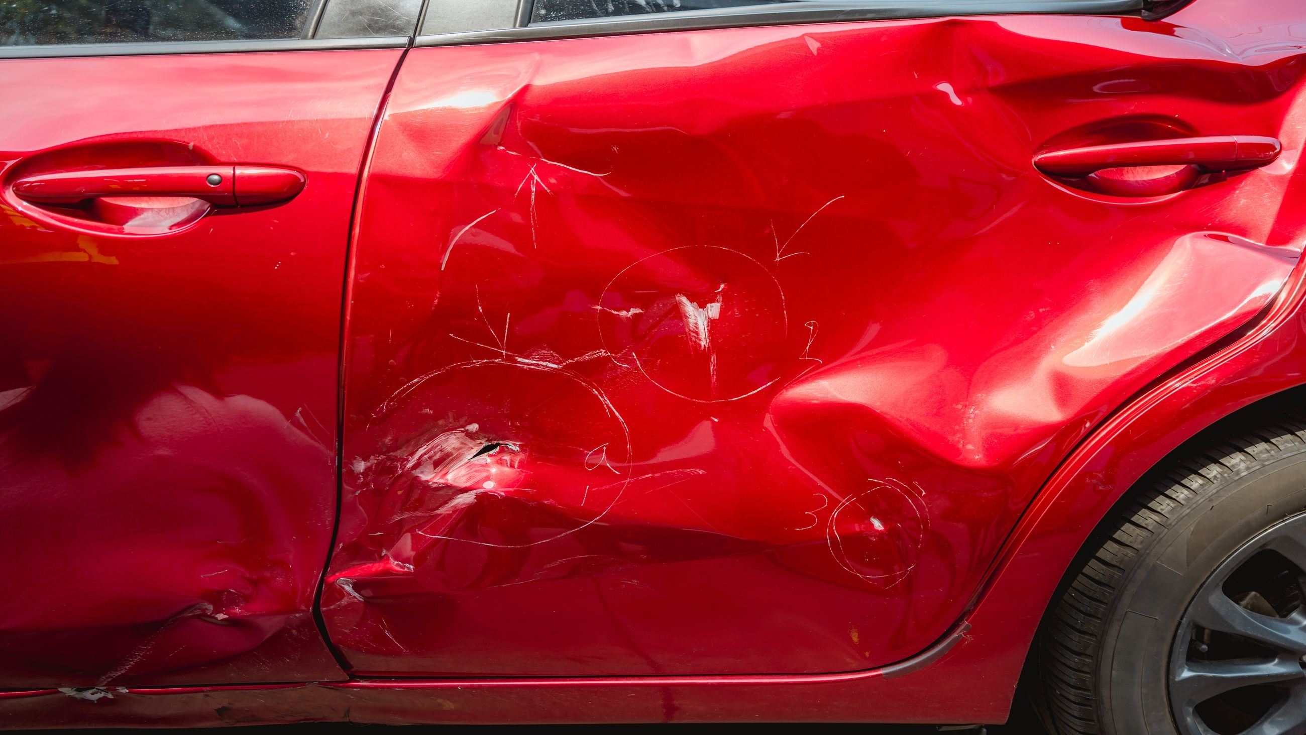 Nahaufnahme einer starken Unfalldelle an der Fahrzeugtür als Beweissicherung für das Schadengutachten