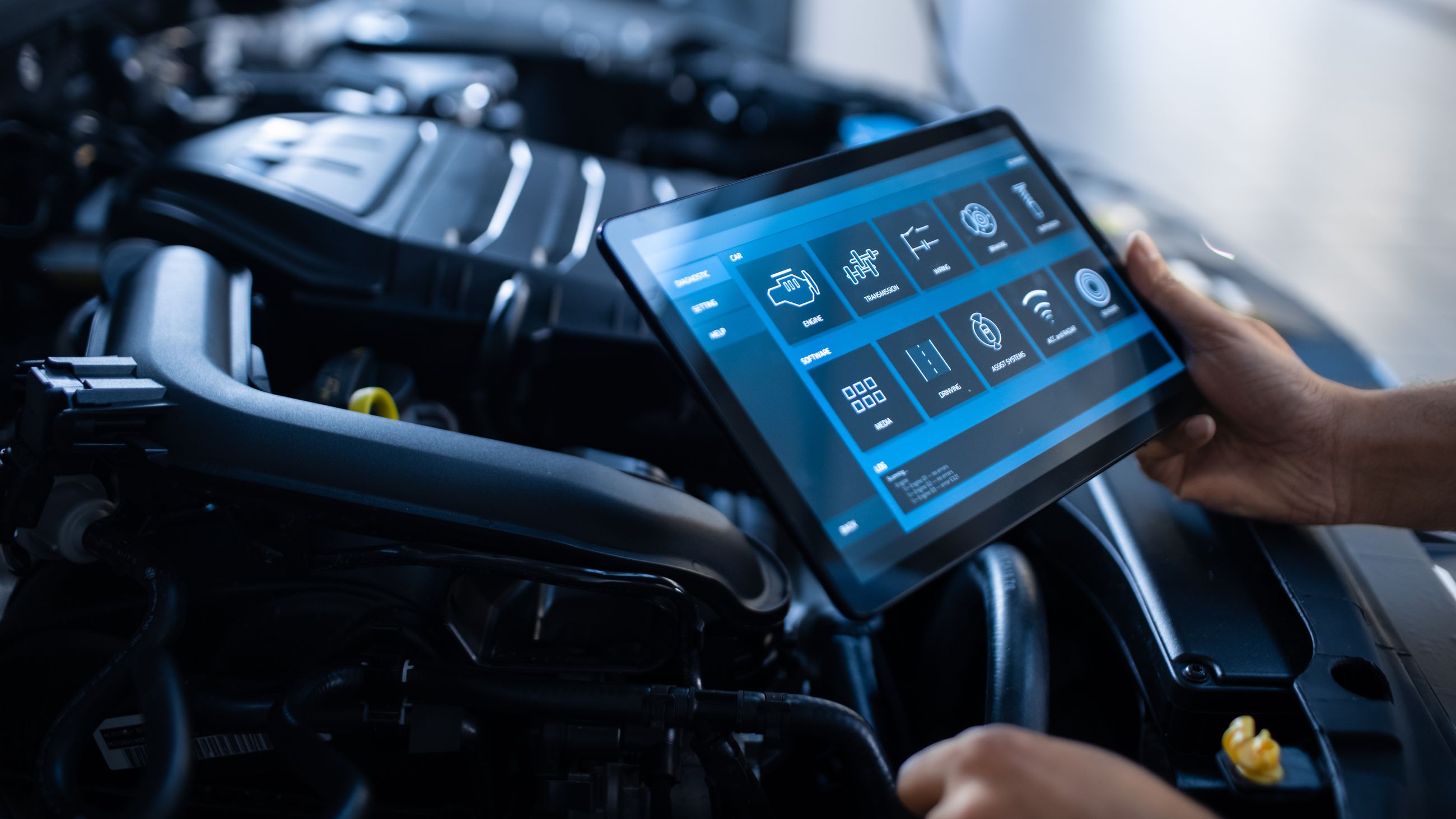 Tablet mit Diagnosesoftware zeigt technische Auswertung über dem geöffneten Motorraum