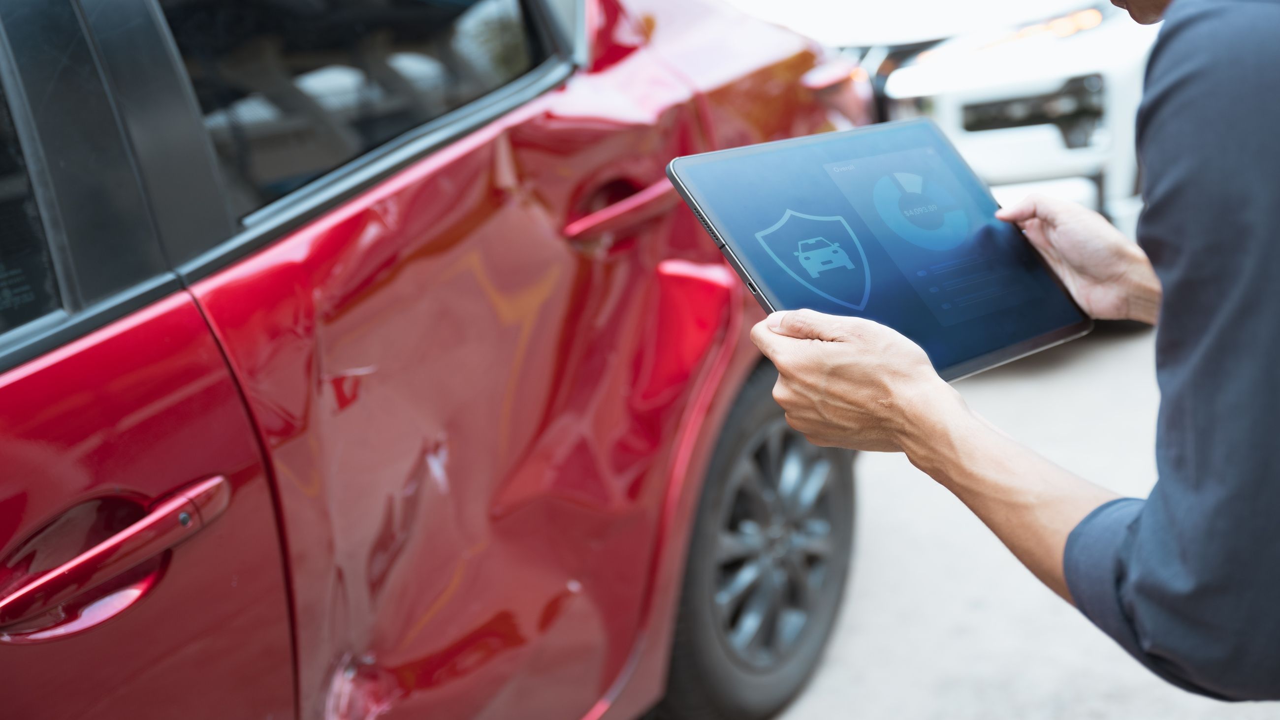 Kfz-Sachverständiger dokumentiert eine Fahrzeugdelle digital per Tablet für das Unfallgutachten