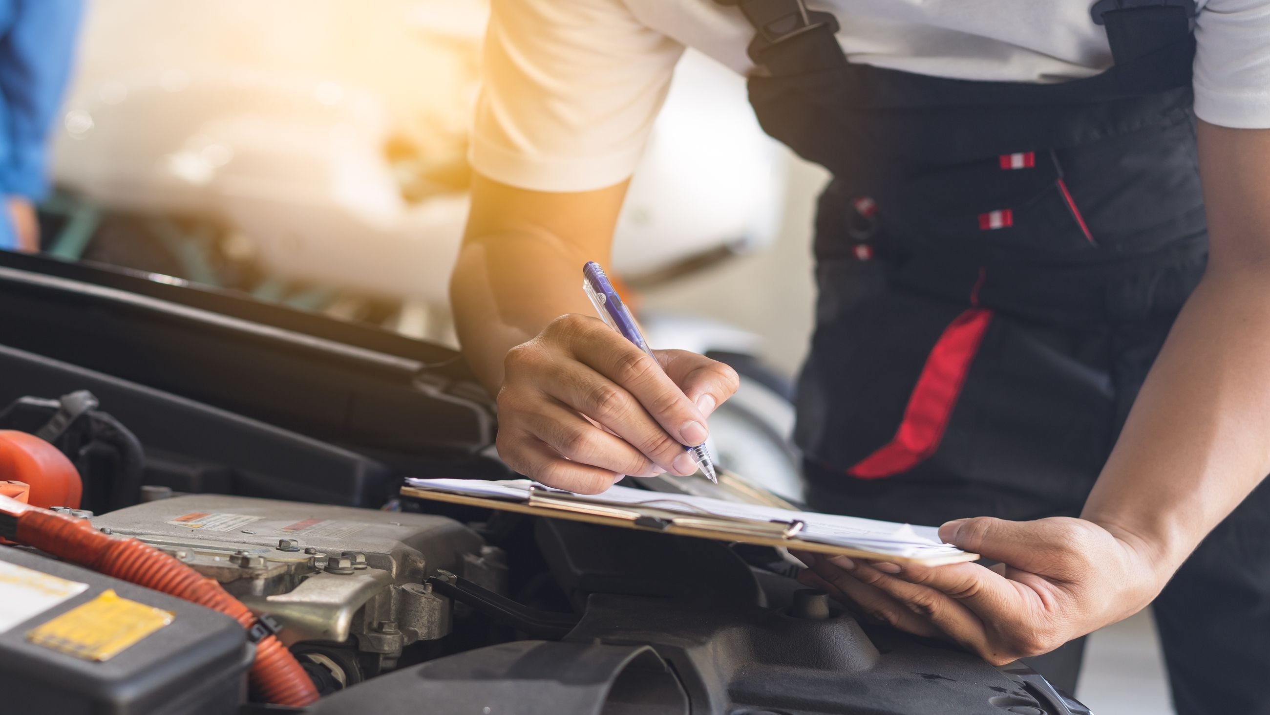 Kfz-Sachverständiger dokumentiert die technische Prüfung im Motorraum auf einem Klemmbrett
